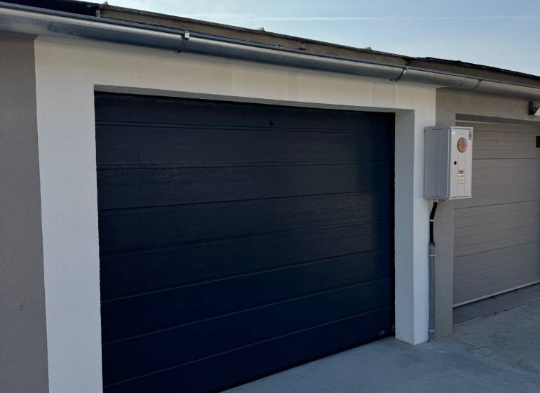 PREDAJ zrekonštruovaná garáž na ulici Slnečná - KOMÁRNO - Brána modernej garáže na Slnečnej ulici v Komárne, vybavená elektrickým ovládaním.