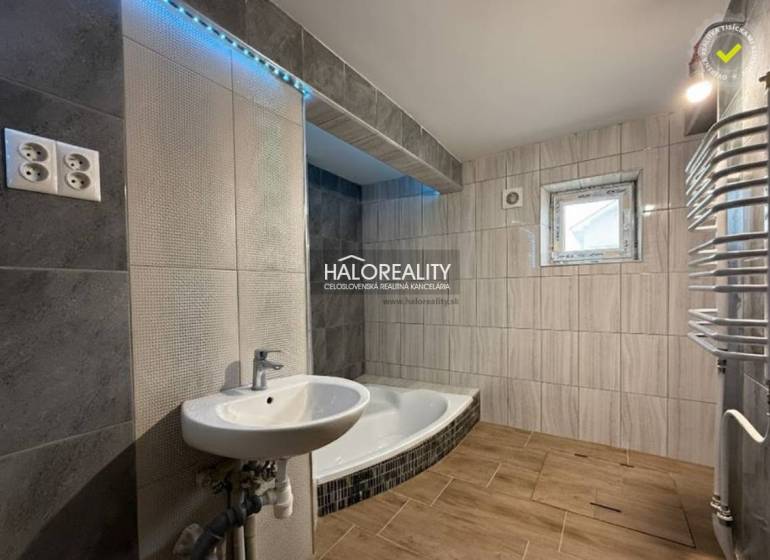 Predaj, rodinný dom Chynorany - Kúpeľňa rodinného domu s vaňou, umývadlom a podlahou s dreveným dekorom.