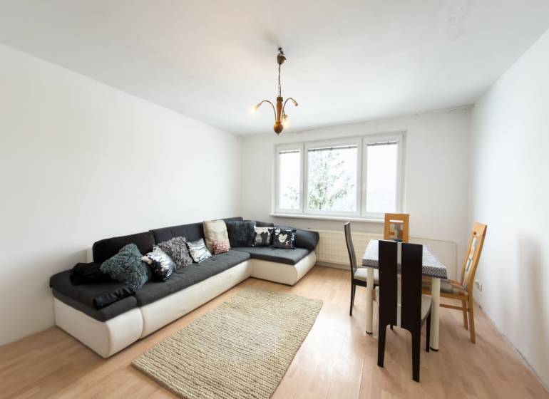 Na predaj 2,5- izbový byt Žilina-Solinky - Obývacia izba v 2-izbovom byte s podlahou s dreveným dekorom, pohovkou a jedálenským stolom.