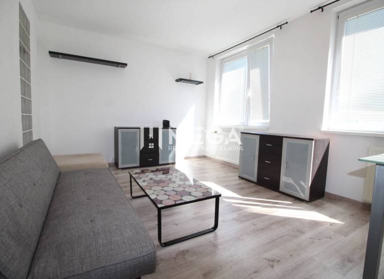 NA PRENÁJOM 1,5-IZB. BYT V MESTE HUMENNÉ - Obývačka v 2-izbovom byte s pohovkou, skleným stolíkom a podlahou s dreveným dekorom.