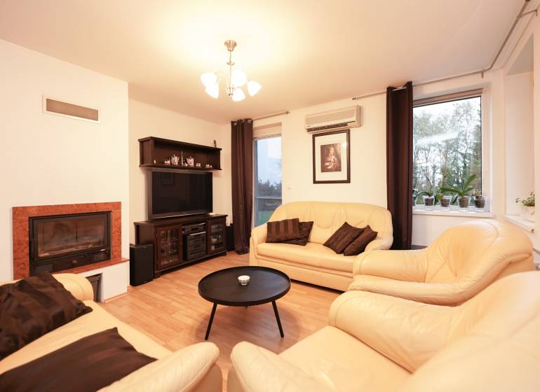 ViNi real / TOP PONUKA! Moderný 4-izb. bungalov s garážou, KVETOSLAVOV - Obývacia izba v rodinnom dome s krbom, koženými sedačkami a podlahou s dreveným dekorom.