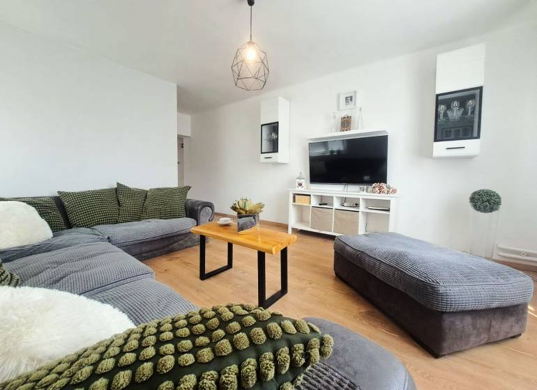 Exkluzívne na predaj 5 izbový rodinný dom - Obývacia izba v rodinnom dome s podlahou s dreveným dekorom a pohodlnou sedacou súpravou.