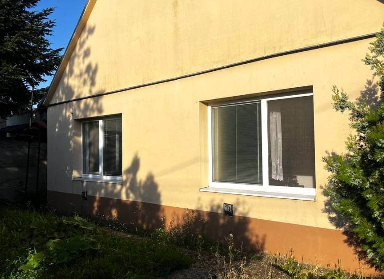 Znížená cena  4-izbový rodinný dom s veľkým pozemkom len 5min od Šale - Rodinný dom v Diakovciach so šikmou strechou a žltou fasádou, obklopený zeleňou.