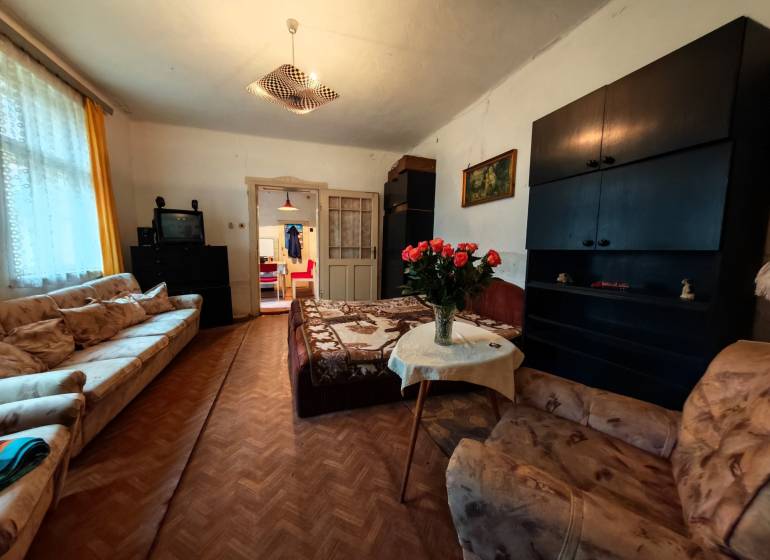 Na predaj rodinný dom v širšom centre mesta Komárno. - Obývacia izba v rodinnom dome s pohovkami, TV a podlahou s dreveným dekorom.