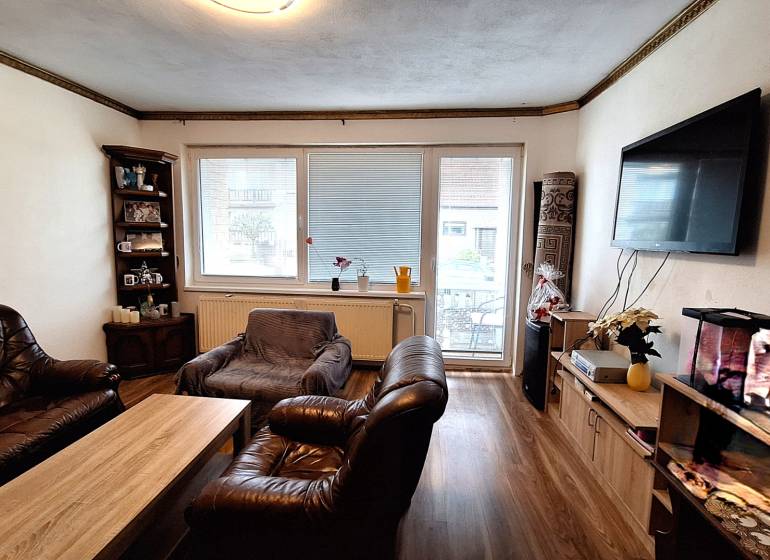 Investujte do budúcnosti - Obývacia izba v rodinnom dome s koženým nábytkom a podlahou s dreveným dekorom.