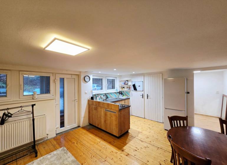 *PRENÁJOM* bezbariérový 1 izbový byt Lesná / Banka - Kuchyňa v 1-izbovom byte s podlahou s dreveným dekorom a stolom.