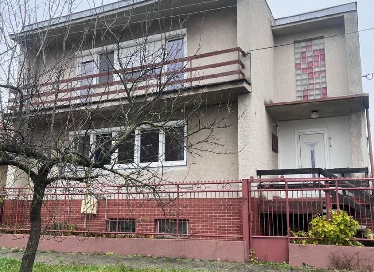 PRIESTRANNÝ 7-IZBOVÝ RODINNÝ DOM S VEĽKÝM POZEMKOM V DLHEJ NAD VÁHOM  - Rodinný dom v Dlhej nad Váhom s betónovou fasádou, balkónom a predzáhradkou.