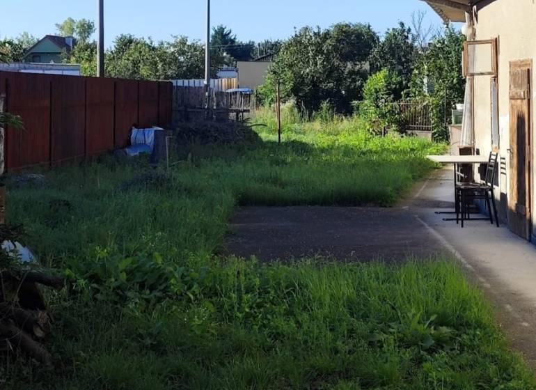 Slnečný pozemok v centre obce Réca, 756 m² - Dvor v Reci vhodný na bývanie, pozemky sú ohraničené plotom a zelenými kríkmi.