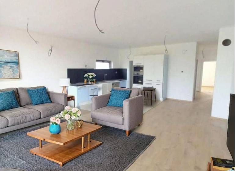 POSLEDNÁ Novostavba 4-izb rodinného domu v lukratívnej časti mesta - Obývacia izba v Rodinnom dome s podlahou s dreveným dekorom, sedačkou a dekoráciami.