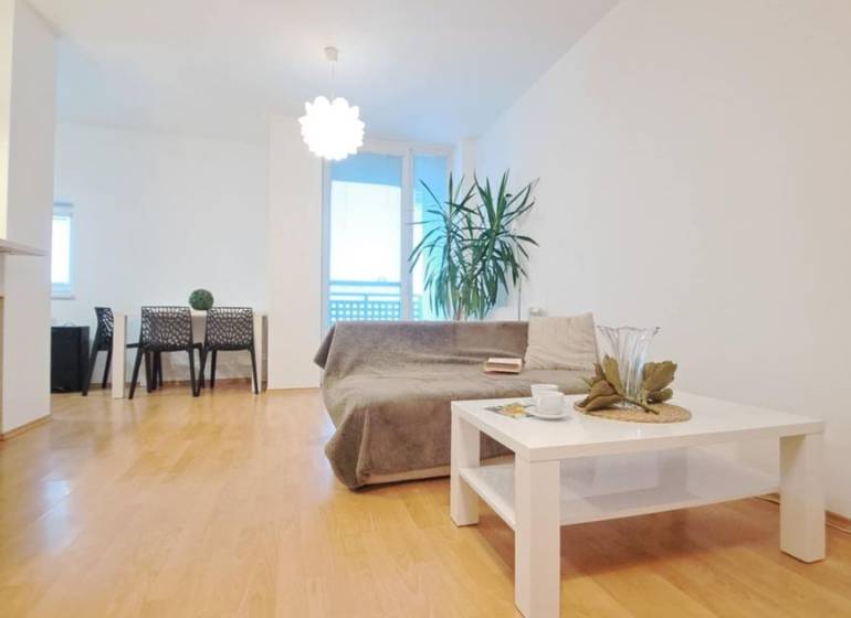 Miesto, kde sa budete cítiť doma–2-izbový byt na sídlisku West-Galana - Obývacia izba v 2-izbovom byte s podlahou s dreveným dekorom, pohovka a konferenčný stolík.