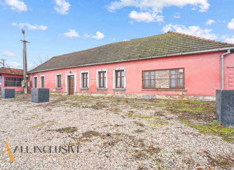 NA PREDAJ 4-IZBOVÝ RODINNÝ DOM V OBCI ŠINTAVA - Rodinný dom v Šintave s kamenným podkladom, ružovou fasádou a drevenými oknami.