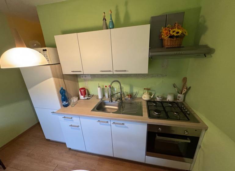 PREDAJ EXKLUZÍVNE: 1i byt s balk.; 41,02 m2; POPRAD; 124.200€ - Kuchyňa v 1-izbovom byte s bielymi skrinkami a podlahou s dreveným dekorom.