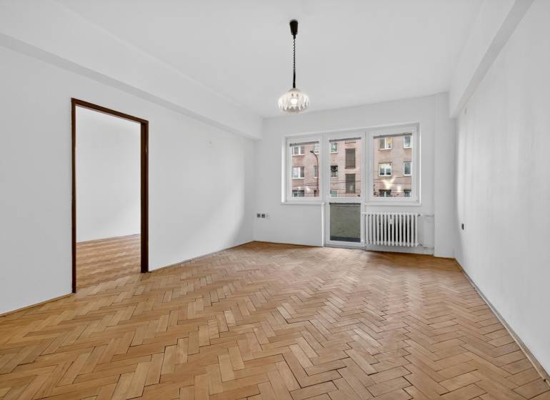 I PREDAJ Priestranný 3-izb. byt v centre Krížna/Blumentálska - Priestranná izba v 3-izbovom byte s podlahou s dreveným dekorom a balkónom.