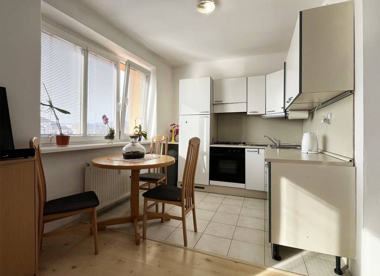 Exkluzívne | Na prenájom priestranný 1i byt Ružinove - Kuchyňa v 1-izbovom byte s okrúhlym stolom a podlahou s dreveným dekorom.