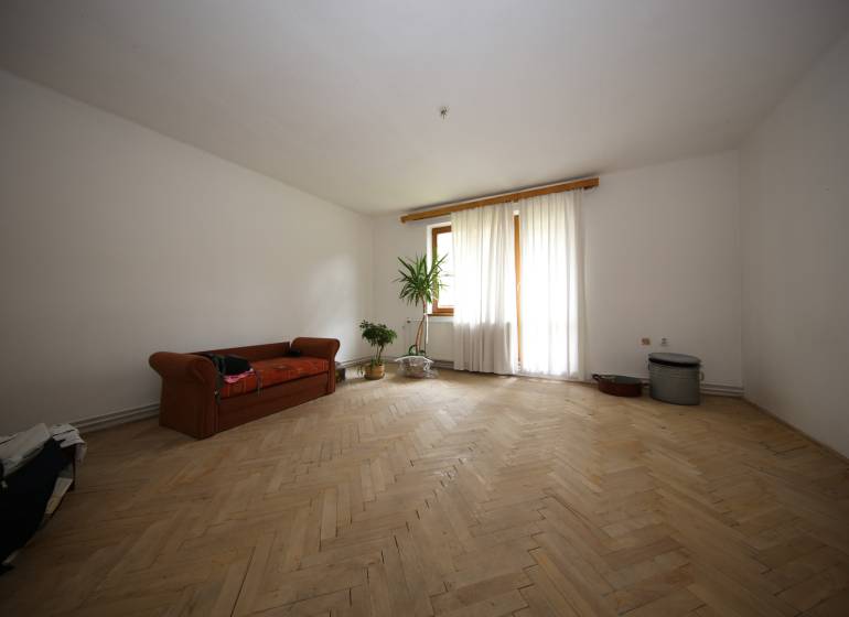 3-izb. byt v rekonštrukcii, Ľubochňa okres Ružomberok - Obývacia izba v 3-izbovom byte s podlahou s dreveným dekorom a gaučom.