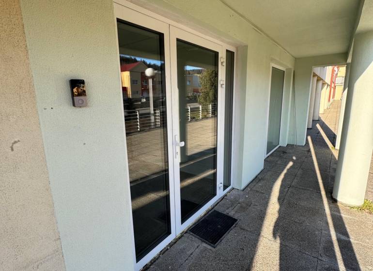 Prenájom obchod/kancelária NP nová kompletná rekonštrukcia, centrum PB - Obchodné priestory na Moyzesovej ulici v Považskej Bystrici s bielymi dverami a sklenenými oknami.