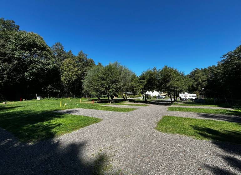 Zabehnutý multifunkčný rekreačný areál (kemp) Kuchyňa na predaj - Rekreačné pozemky v Kuchyni s karavanmi obklopené stromami a modrou oblohou.