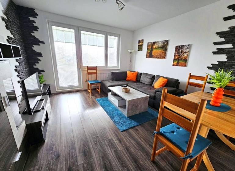 Útulný byt s loggiou a klimatizáciou, Rovniankova.Províziu neplatíte - Obývacia izba v 3-izbovom byte so sedačkou, TV a podlahou s dreveným dekorom.