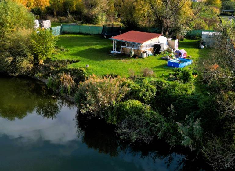 KH-1018, PREDAJ Pozemok pri jazere 887 m², garáž, altánok - Pokojná chatka pri rieke obklopená zeleňou a stromami v okolí Čane, výstavba domov.