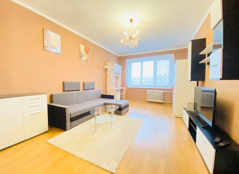 NA PRENÁJOM 2-IZBOVÝ BYT, NÁRODNÁ TRIEDA - Obývacia izba v 2-izbovom byte s podlahou s dreveným dekorom, sedačka, nábytok, luster.