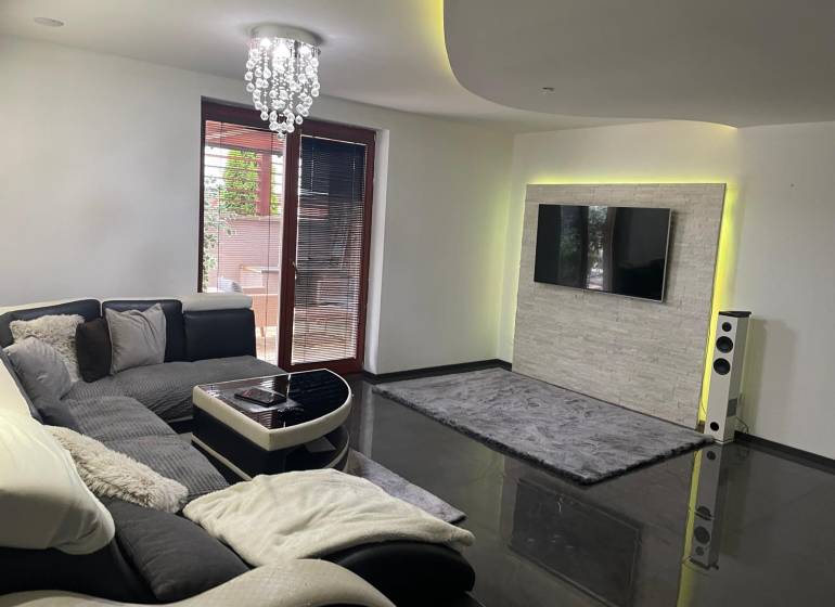 Moderný zariadený rodinný dom na prenájom 120m2 s terasou Košice Barca - Obývačka v rodinnom dome so sedačkou a televízorom na stene s kamenným obkladom.