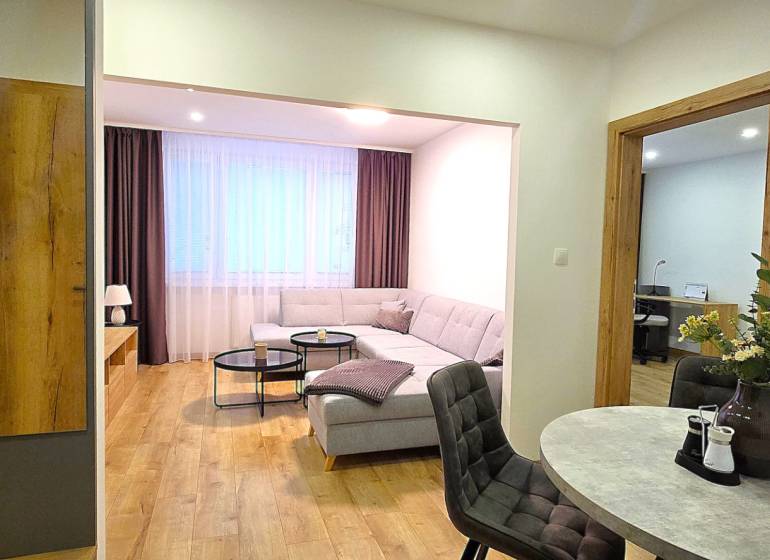 Prenájom komfortný, zariadený 3 izbový byt po úplnej rekonštrukcii - Obývacia izba 3-izbového bytu so sedačkou, stolíkom a podlahou s dreveným dekorom.