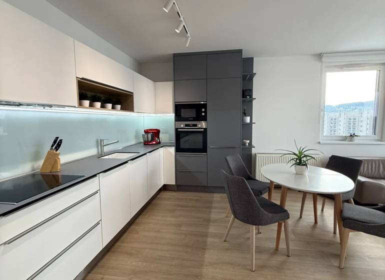 3-izb. byt, Martina Granca, Dúbravka, novostavba Pekná výhliadka - Kuchyňa v 3-izbovom byte s podlahou s dreveným dekorom a jedálenským stolom.