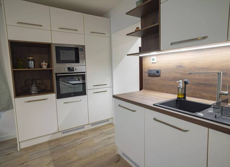 2,5 izb. byt, ul. Jelenia, Staré Mesto,tehlový dom, po rekonštrukcii - Kuchyňa s bielymi skrinkami, drevenou pracovnou doskou, vstavanými spotrebičmi v 3-izbovom byte na ulici Jelenia.