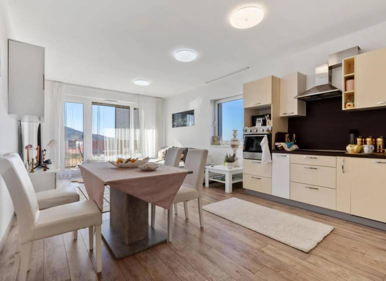 Novostavba 3-izb. bytu s parkovacím státím, ul.Hany Ponickej, Lamač - Jedálenská časť v 3-izbovom byte s kuchynskou linkou a podlahou s dreveným dekorom.