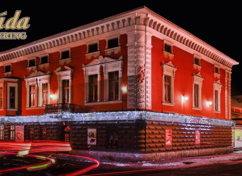 Predaj lukratívneho polyfunkčného objektu v Poprade - Nocou osvetlená budova hotela s červenou fasádou v Poprade. Hotely a penzióny.