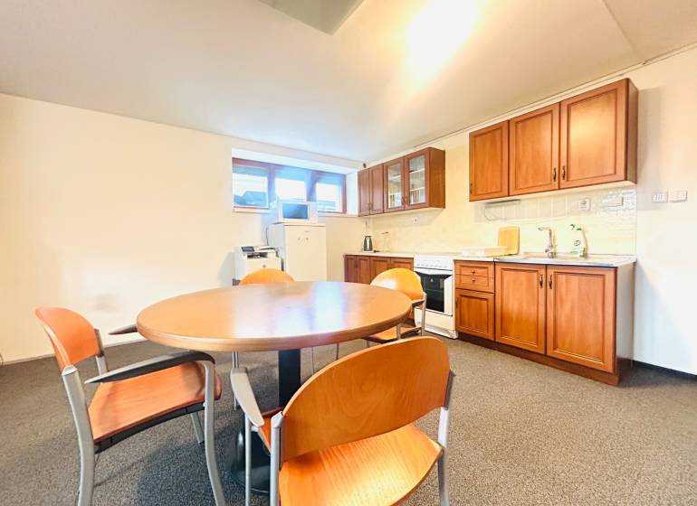 PRENÁJOM- KANCELÁRSKÝ PRIESTOR -120m2- KOMÁROVSKÁ - Kuchyňa v rodinnom dome s jedálenským stolom, stoličkami a kuchynskou linkou s dreveným dekorom.