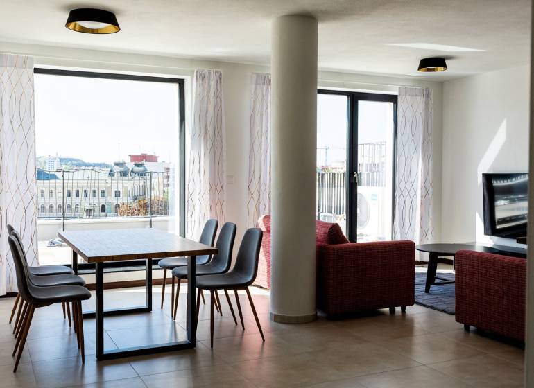 PRENÁJOM 3 izbový luxusný byt  v centre Nitry s veľkou terasou - Obývacia izba v 3-izbovom byte s jedálenským stolom a výhľadom na mesto.