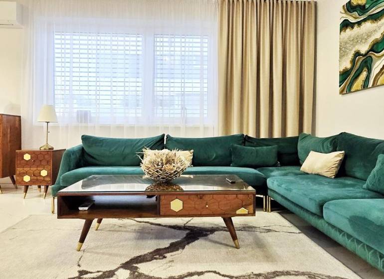 - KRÁTKODOBÝ PRENÁJOM - RODINNÝ DOM - 105 m2 - ROVINKA - Rodinný dom s pohovkou v zelenom odtieni, drevený nábytok a umenie na stene.