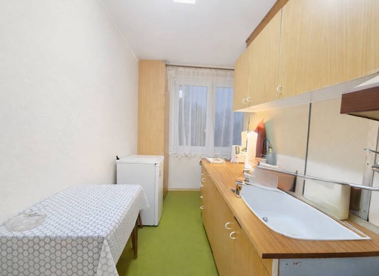 Predaj pôvodného 3+1 bytu v žiadanej lokalite v Čadci (MO) - Kuchyňa v 3-izbovom byte s jednoduchým zariadením, podlaha s dreveným dekorom.