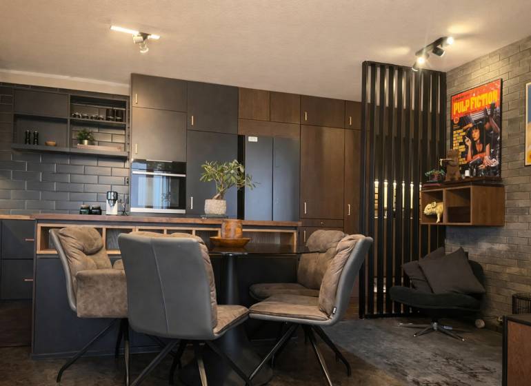 2-izbový byt v Pezinku s vlastným parkovaním - REZERVOVANÉ - Kuchyňa v 2-izbovom byte s tmavými skrinkami a dekoratívnymi plagátmi na stene.