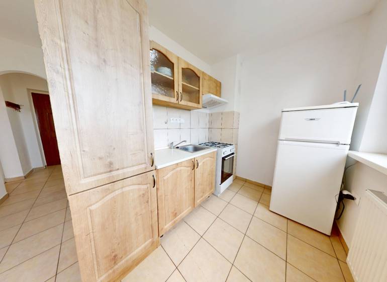 Na prenájom 2 izbový byt, Dežerice - Kuchyňa v 2-izbovom byte s dlažbou, skrinkami a bielymi spotrebičmi.