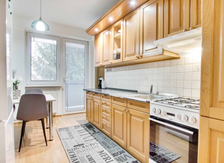 Na prenájom veľký 4-izbový byt s balkónom, garážou a záhradou, Kolta – - Kuchyňa v 4-izbovom byte s podlahou s dreveným dekorom a jedálenským stolom.