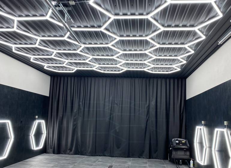 Ponuka na odstupenie detailingového štúdia a autoumyvárne v Prievidzi - Obchodné priestory s tmavým dekorom a šesťuholníkovým LED osvetlením na strope a stenách.