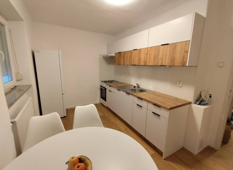 Na prenájom 2-izbový byt  Nové Zámky - Kuchyňa v 2-izbovom byte so svetlými skrinkami a podlahou s dreveným dekorom.