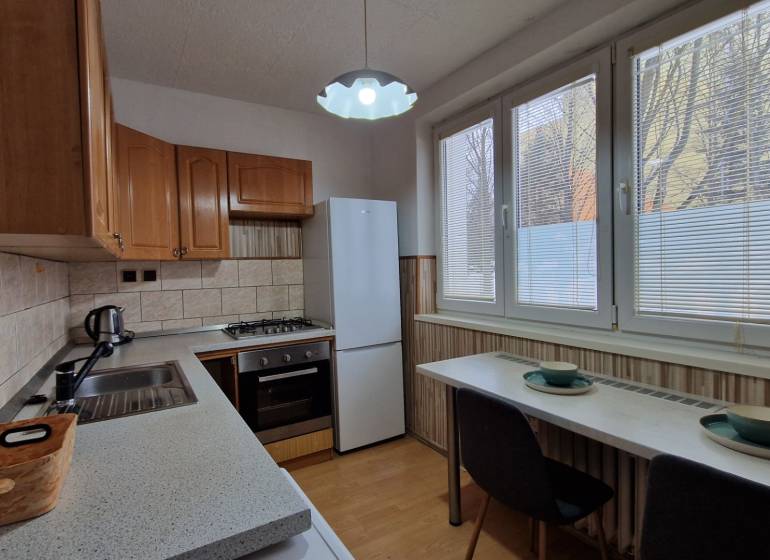 AstonReal:  predaj 2-izbový byt 54 m2, Poprad - Západ, Komenského - Kuchyňa v 2-izbovom byte so spotrebičmi a podlahou s dreveným dekorom.