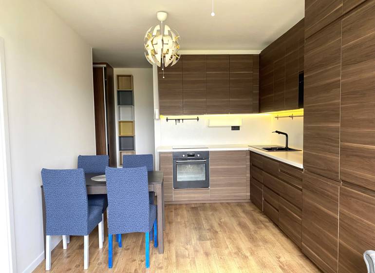 PRENÁJOM NÁDHERNÝ 3-IZBOVÝ BYT MAMAPAPA BA IV DÚBRAVKA - Kuchyňa v 3-izbovom byte s jedálenským stolom, moderným osvetlením a podlahou s dreveným dekorom.