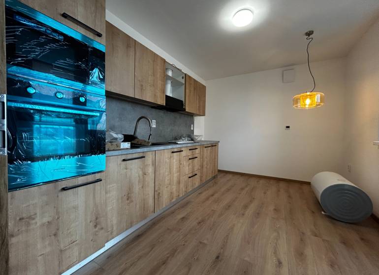 3-izbový byt v štandarde vrátane kuchyne len 15 minút od BA - Kuchyňa v 4-izbovom byte s podlahou s dreveným dekorom a zaveseným svietidlom.