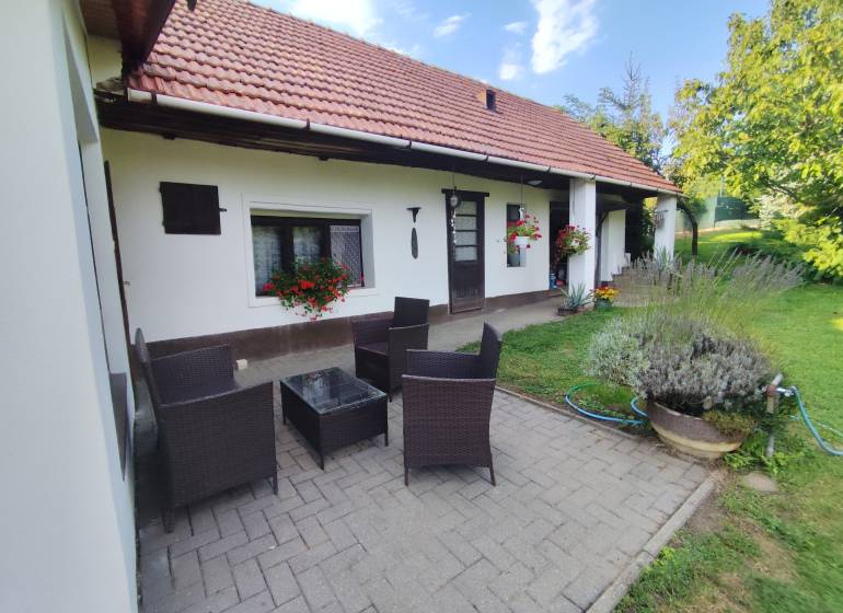 Ponúkame na predaj záhradný domček - Jasová - Rodinný dom v Jasovej s terasou, ratanovým nábytkom a upravenou záhradou.