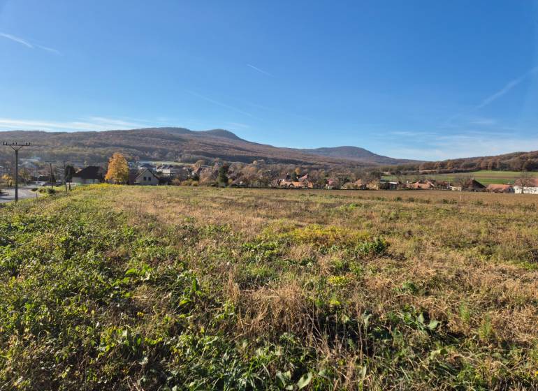 Stavebný pozemok, Velčice, 981 m2, okr. Zlaté Moravce - Výhľad na Pozemky - bývanie vo Velčiciach s kopcovitou krajinou v pozadí.