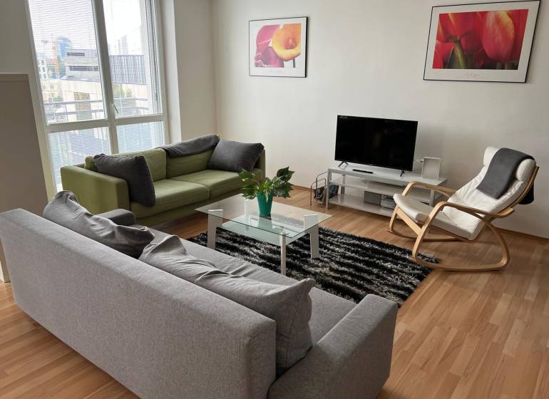 Slnečný 2i byt s balkónmi pri NC Nivy - Svetlá obývacia izba s gaučami, kreslom a televízorom v 2-izbovom byte.