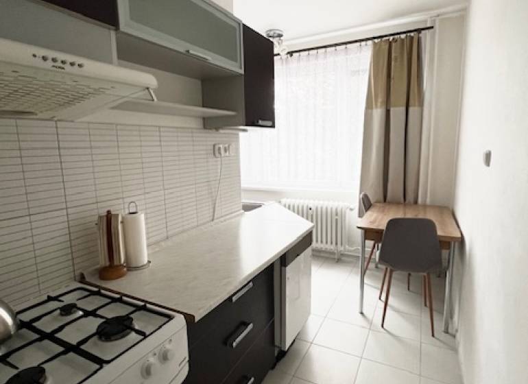 Ponuka na prenájom 2,5 izbový byt Zl. Potok - Kuchyňa v 2-izbovom byte so sporákom, tmavým nábytkom a svetlou dlažbou.