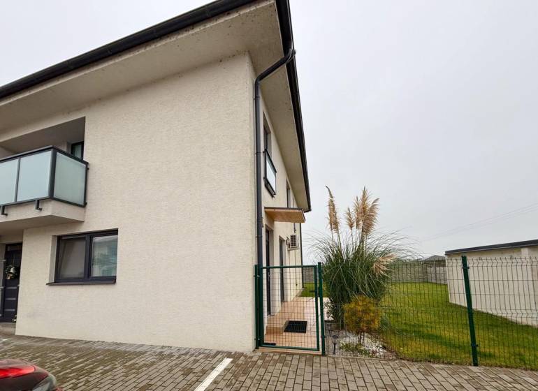Moderný 3-izbový byt so záhradou Šamorín-Kráľovianky - Exteriér 3-izbového bytu na ulici Kráľovianky v meste Kráľovianky, pri vchode rastliny a trávnik.
