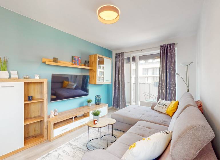 BA/PETRŽALKA-Prenájom moderného 3i bytu s parkovacím státim-Slnečnice - Obývacia izba v 3-izbovom byte s pohodlnou sedačkou a balkónom, podlaha s dreveným dekorom.