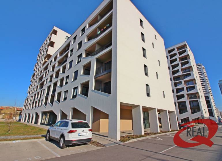 **VONKAJŠIE PARKOVACIE STÁTIE**NOVOSTAVBA KOPČIANKA** - Budova s parkoviskom v Bratislave-Petržalke na Ulici Závodu Matador so zaparkovaným autom.