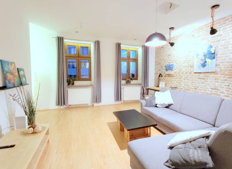 JEDINEČNÝ 2i byt, REKONŠT., 2 X .SAMOST.IZBA, Hviezdoslavovo nám.  - Obývačka, tehlová stena, sivá sedačka, drevená podlaha, na ulici Hviezdoslavovo námestie, pohoda 2-izbový byt.